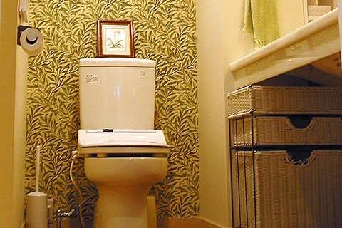 トイレは洗面と一体で広々。入って正面になる壁面は、落ち着ける草模様の壁紙で仕上げた。